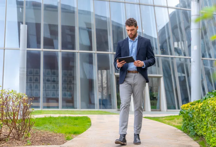 Professional reviewing job opportunities on a tablet outside an office